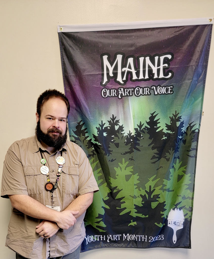 Westbrook High School Art teacher Matthew Johnson standing next to Maine Youth Art Month Flag